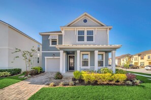 A two-story house with a front porch, a small garden, and a driveway.