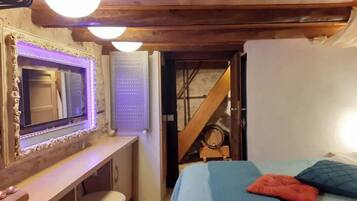 A bedroom with a bed, a mirror, a desk, and a staircase.