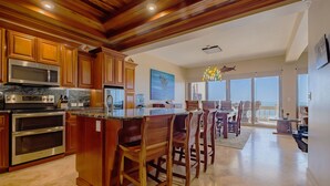A spacious kitchen with wooden cabinets, stainless steel appliances, and a large island. - Ocean’s Edge 4B – Fourth-Floor Beachfront Condo with Wrap-Around Ocean Views (Ambergris Caye)