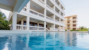 A multi-story hotel with a swimming pool in the foreground. - Ocean’s Edge 4B – Fourth-Floor Beachfront Condo with Wrap-Around Ocean Views (Ambergris Caye)