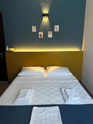Habitación de hotel con cama, cabecero, lámpara fijada a la pared y cuadro enmarcado.