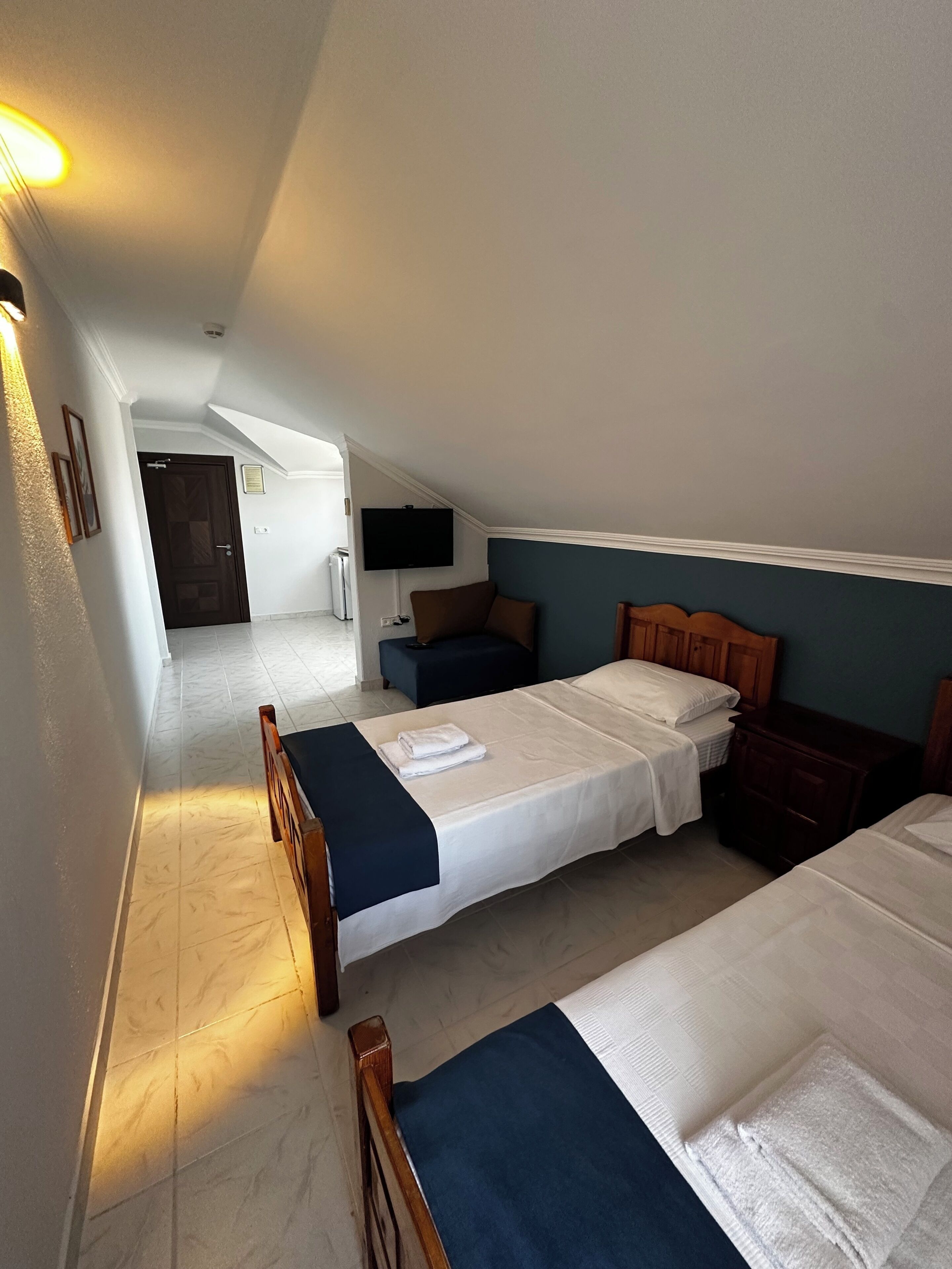 Ein Zimmer mit zwei Betten, einem Fernseher und einer hölzernen Sitzbank.