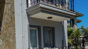 A building with a stone facade, a balcony with wrought iron railings, and a well-maintained green bush in front. - Sirius Star (Ortaca)