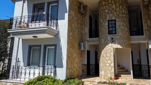 A two-story building with a stone facade, a balcony with wrought iron railings, and a staircase leading to an upper level. - Sirius Star (Ortaca)