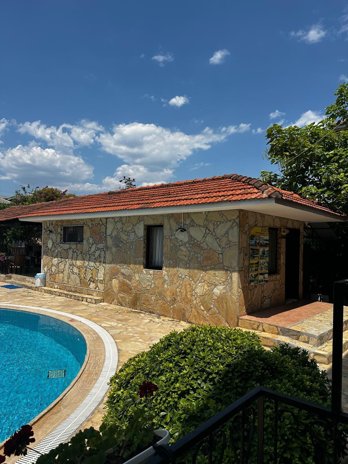 A stone building with a red-tiled roof, a swimming pool, and a small garden area.