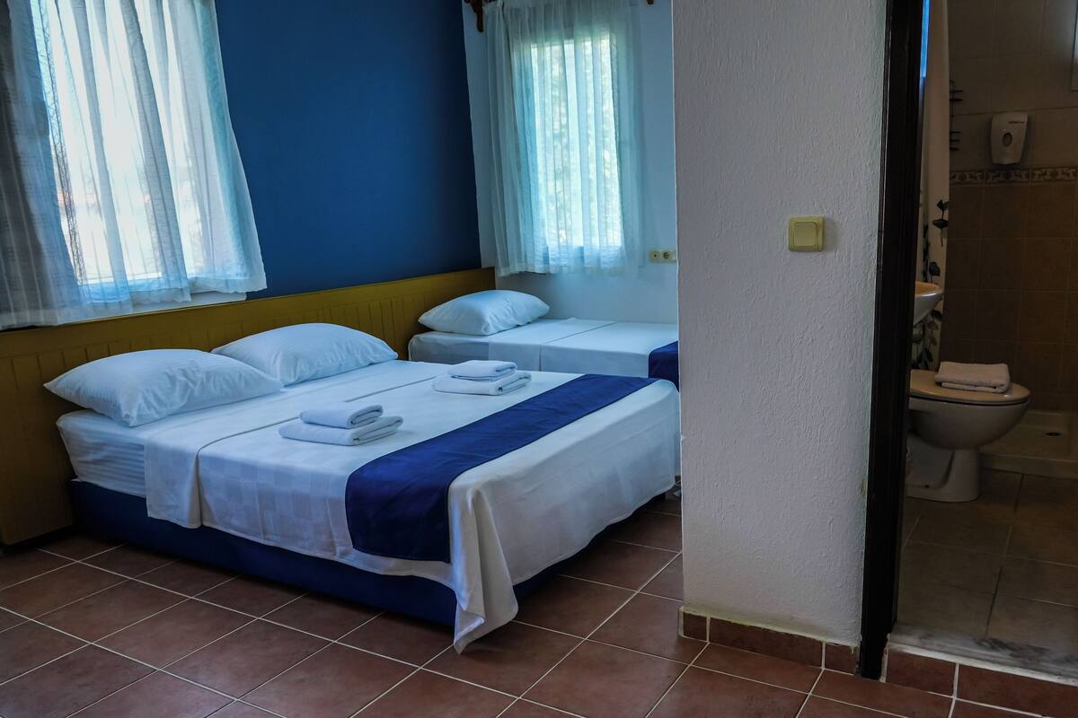 Habitación de hotel con dos camas, un baño con inodoro y zona de ducha.