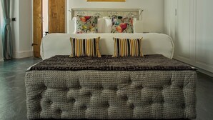 Une chambre à coucher avec un grand lit, deux oreillers, une tête de lit à motifs floraux et un tableau coloré au-dessus du lit.