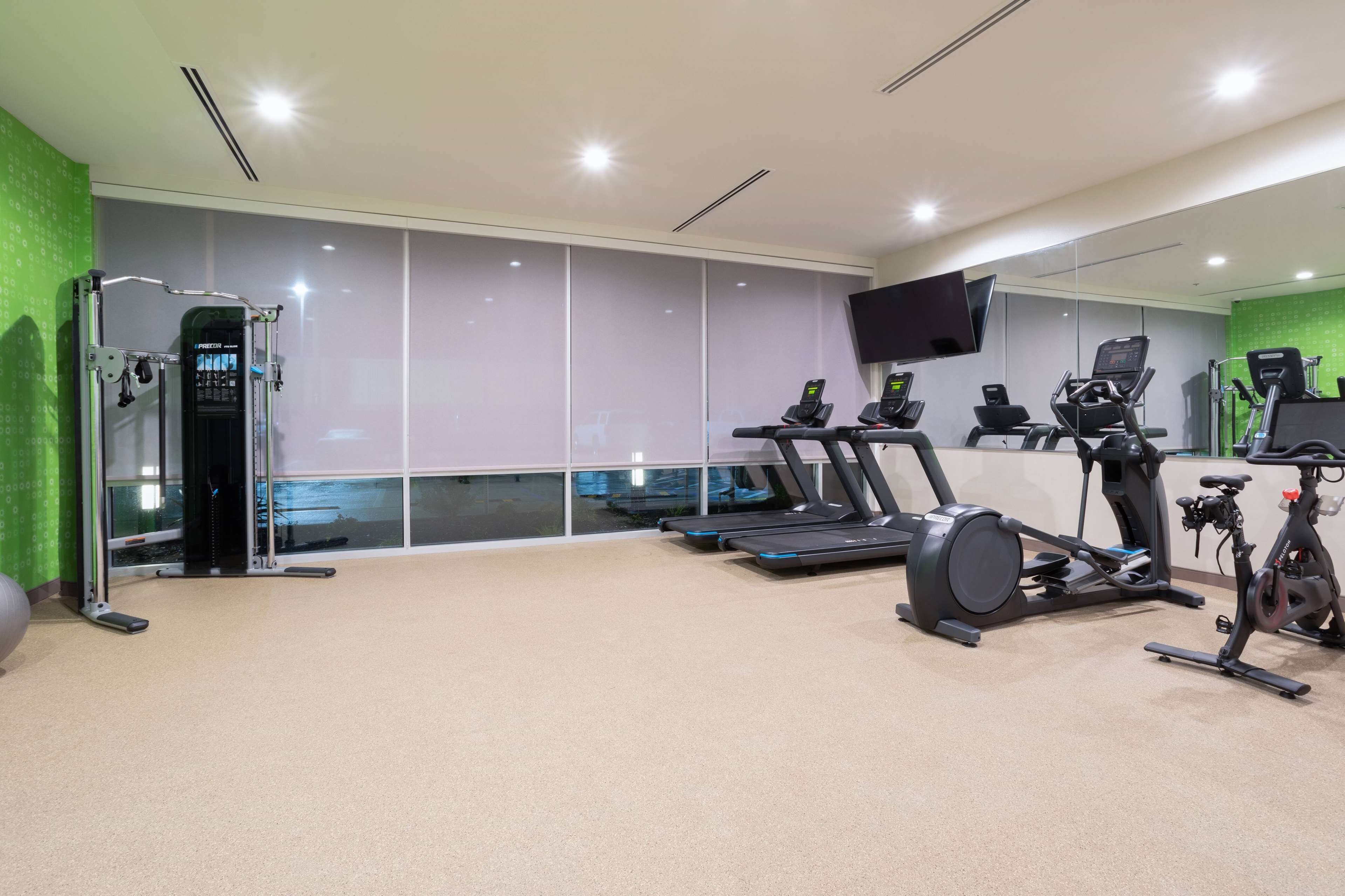 Un gimnasio moderno con cintas de correr, bicicletas estáticas y una máquina de pesas.