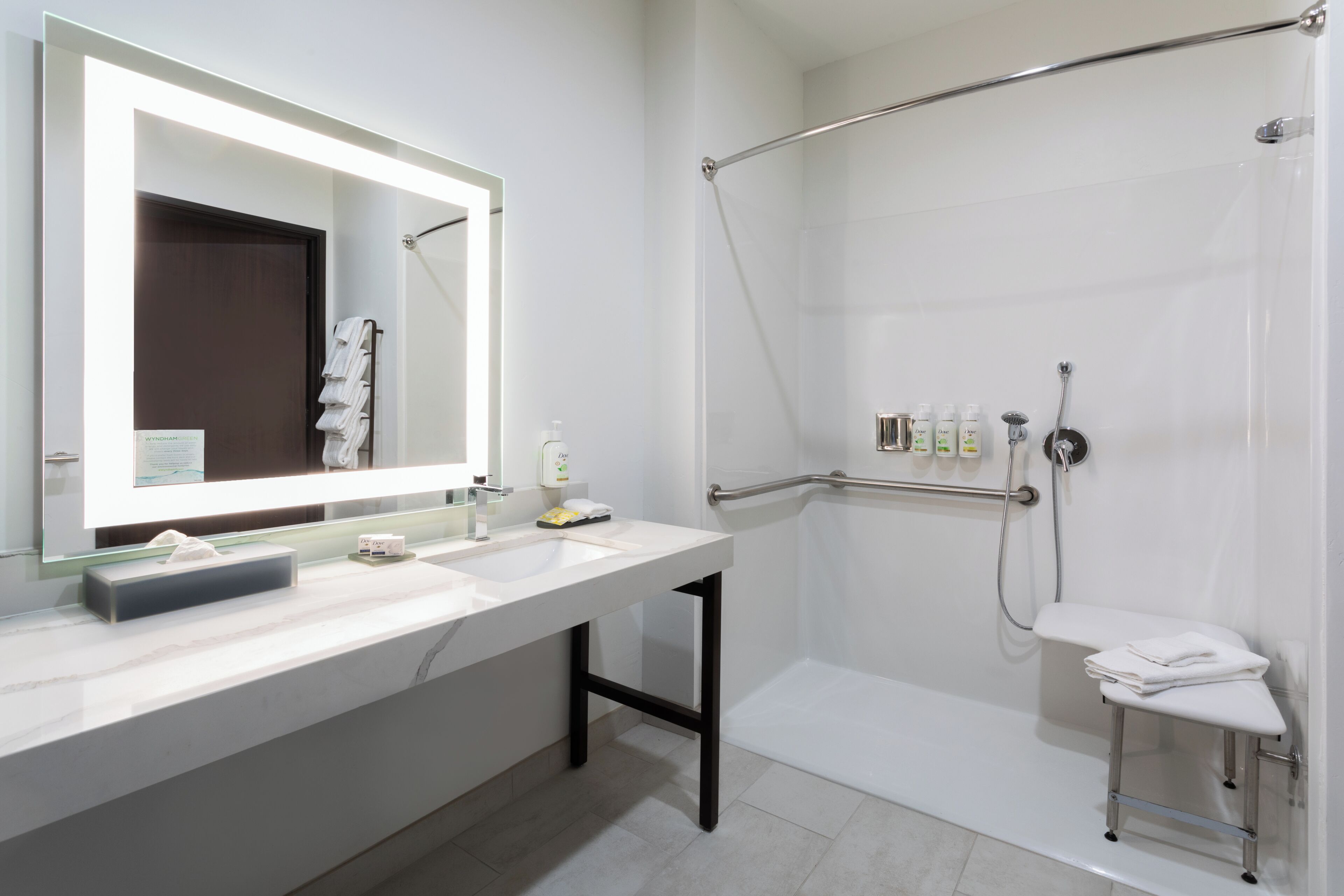Un baño moderno con un espejo grande, dos lavamanos, una ducha con puerta de vidrio y un perchero para toallas.