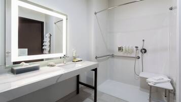 Un baño moderno con un espejo grande, dos lavamanos, una ducha con puerta de vidrio y un perchero para toallas.