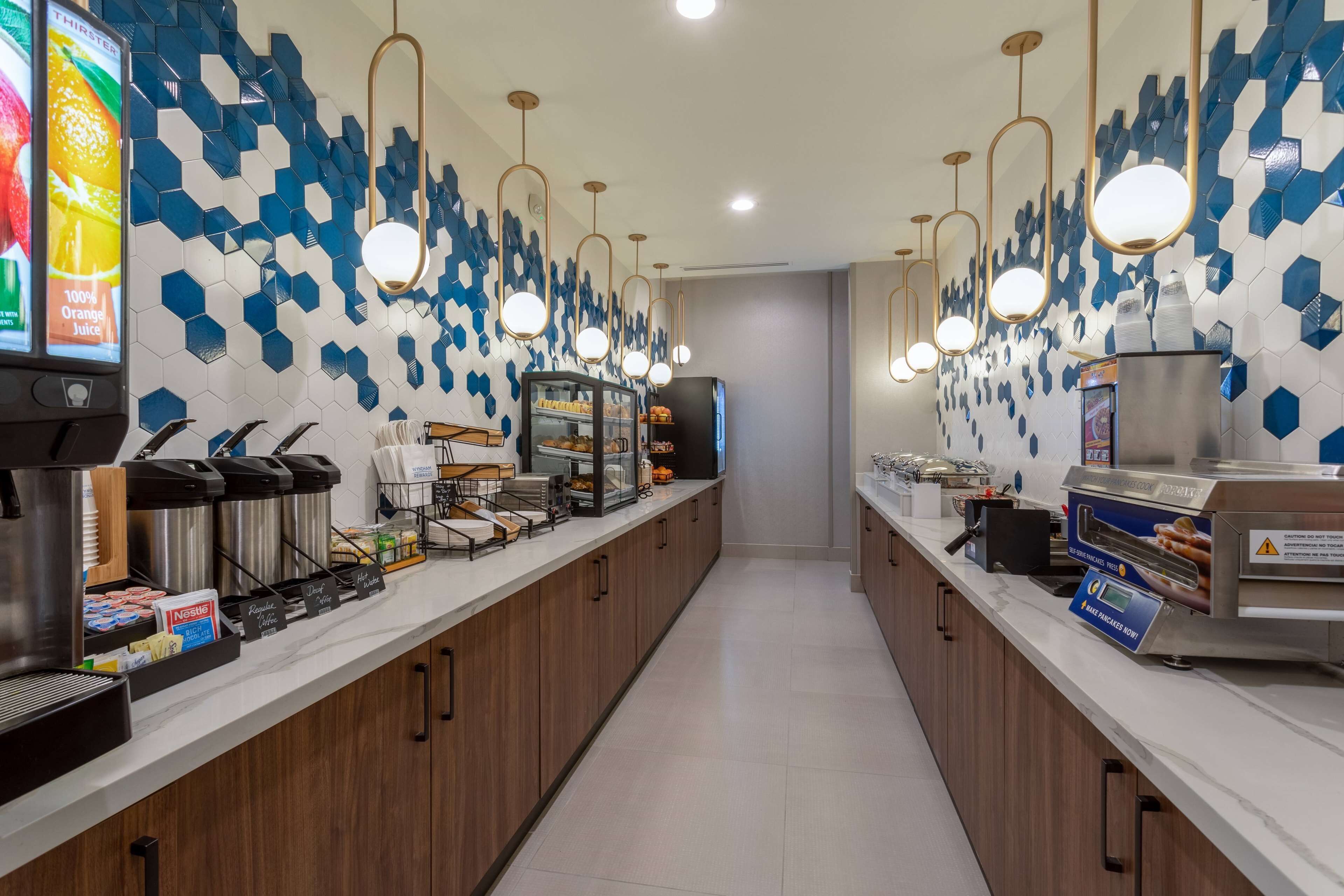 Una barra de desayuno moderna con salpicadero de azulejos hexagonales, electrodomésticos de acero inoxidable e iluminación colgante.