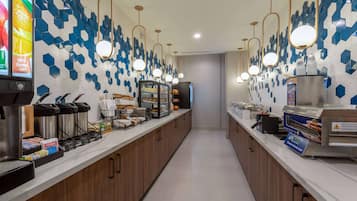 Una barra de desayuno moderna con salpicadero de azulejos hexagonales, electrodomésticos de acero inoxidable e iluminación colgante.