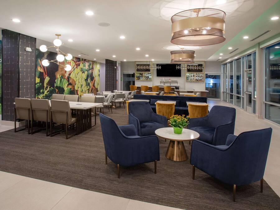 A modern hotel lobby with a dining area, seating arrangements, and a bar.
