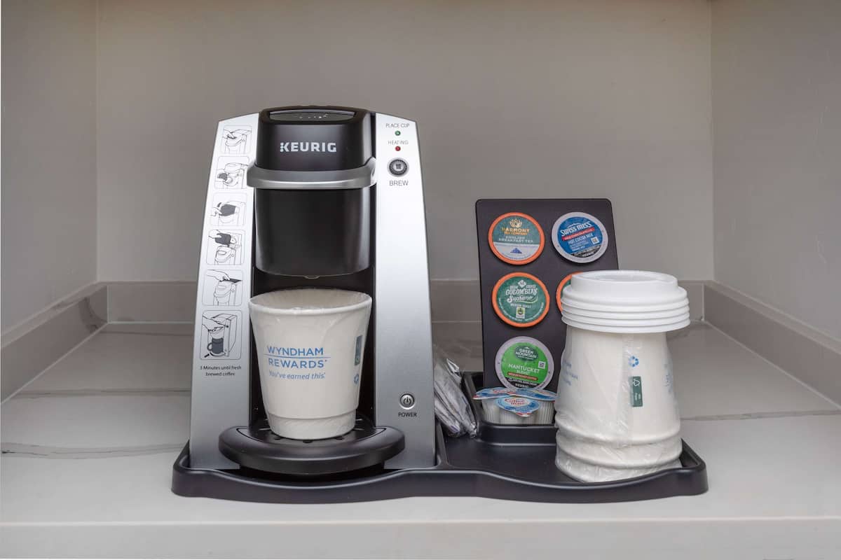 A Keurig coffee machine with a cup of coffee and a reusable cup holder.