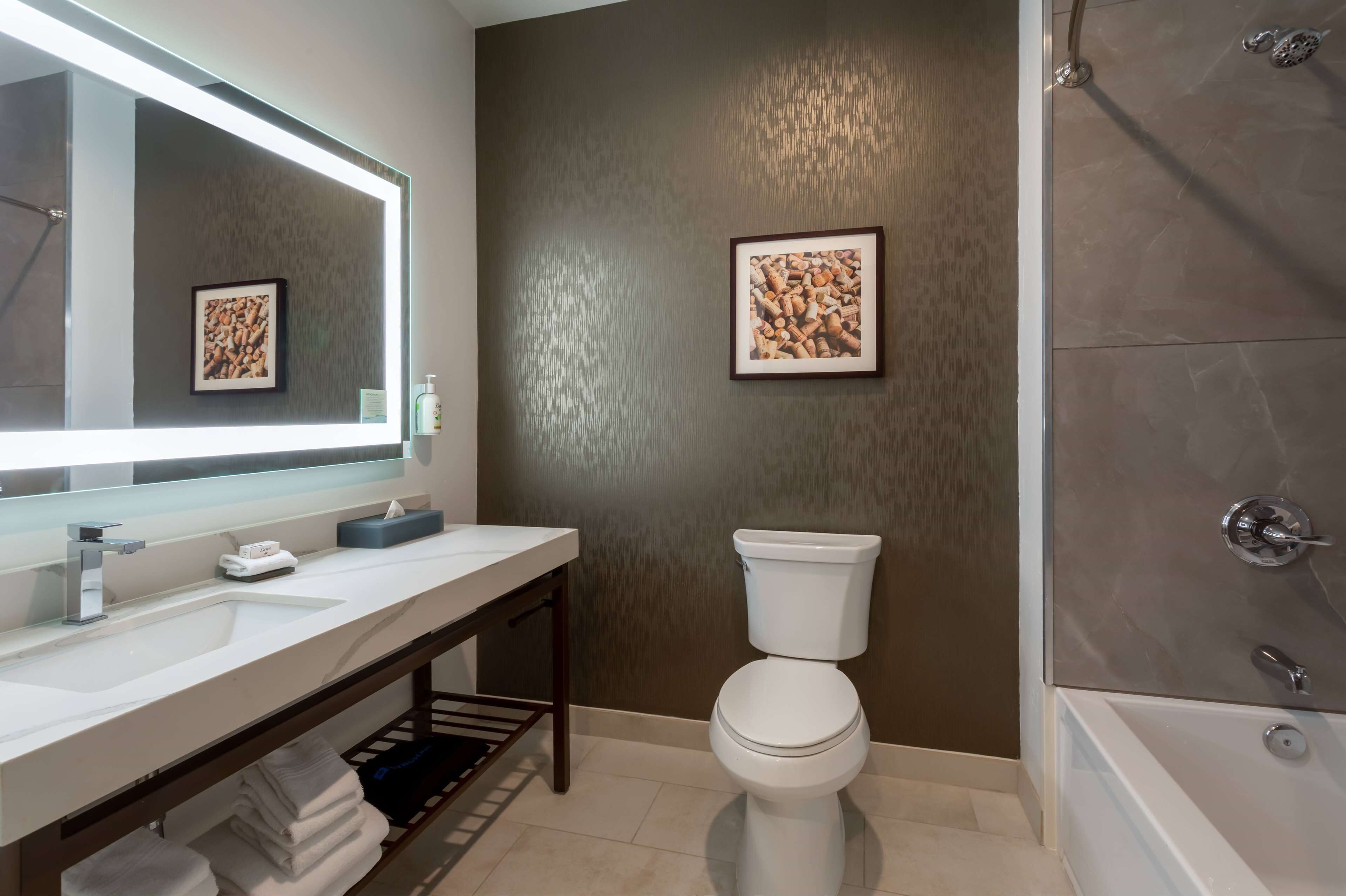 Un baño moderno con un espejo grande, un lavabo blanco, un inodoro y una bañera.
