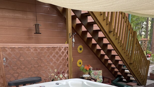 Un bain à remous installé dans un espace extérieur en bois, avec un escalier en bois et une clôture à treillis.