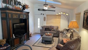 Un salon équipé d’un téléviseur, de canapés, d’une table basse et d’un ventilateur de plafond.
