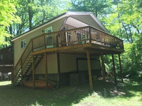 Ein zweistöckiges Haus mit einer Holzterrasse und einer Treppe, die zum oberen Stockwerk führt.