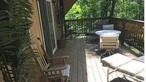 A wooden deck with a table and chairs, surrounded by greenery. - Serene location in middle of wine country  (Westfield)