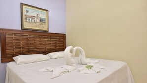 A neatly made bed with a wooden headboard, a framed painting above it, and a simple, clean room layout. - Pousada Pôr do Sol (Paraty)