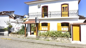 A two-story building with a balcony, yellow shutters, and a tiled roof. - Pousada Pôr do Sol (Paraty)