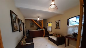 A spacious living area with a sofa, a small table with a plant, and a staircase leading to another level. - Pousada Pôr do Sol (Paraty)