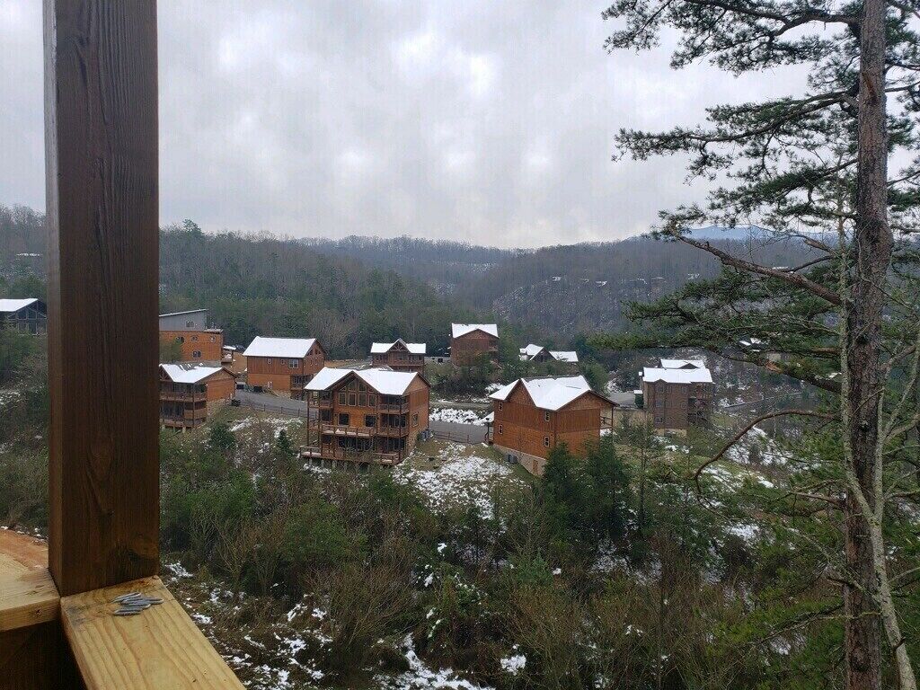 A view of a resort with multiple wooden buildings, surrounded by trees and a mountainous backdrop.