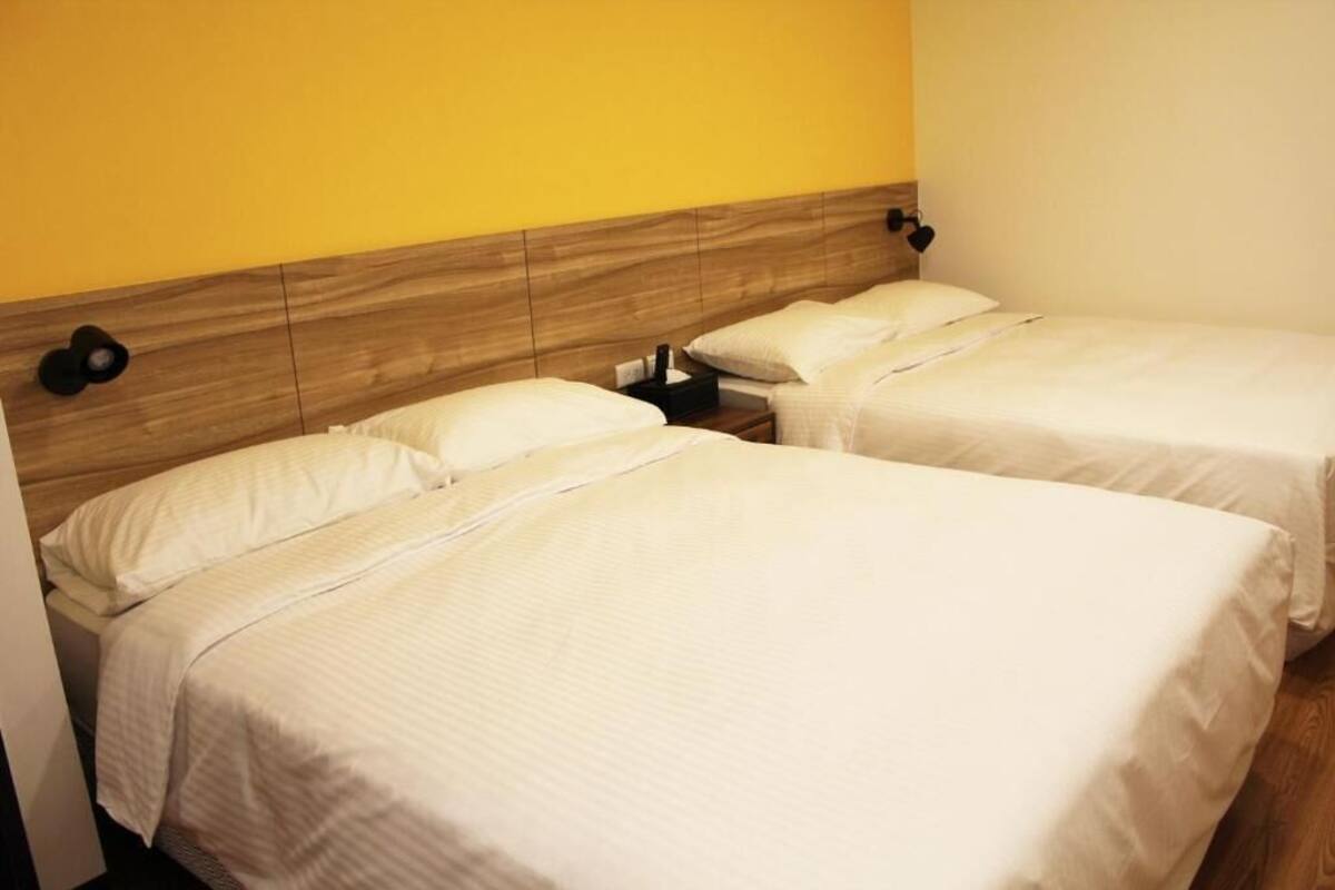 Two single beds with wooden headboards, white bedding, and a bedside table with a lamp.