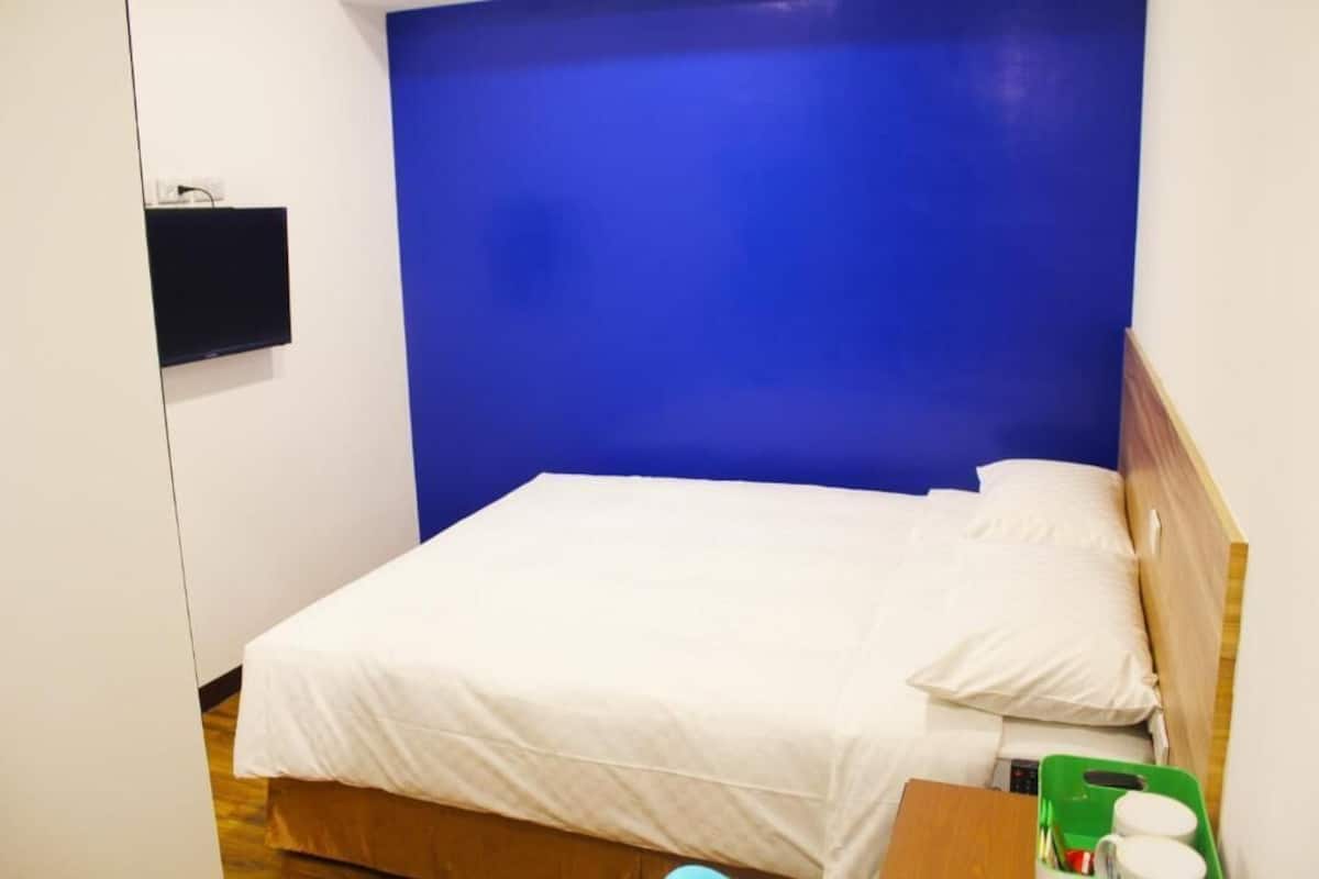 A single bed with white bedding in a room with a blue accent wall.