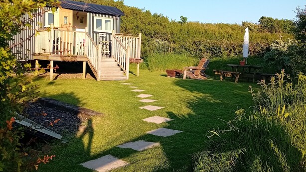 A house with a deck and a garden with stepping stones. - stayinhartland @ Quincecote shepherds hut (Hartland)