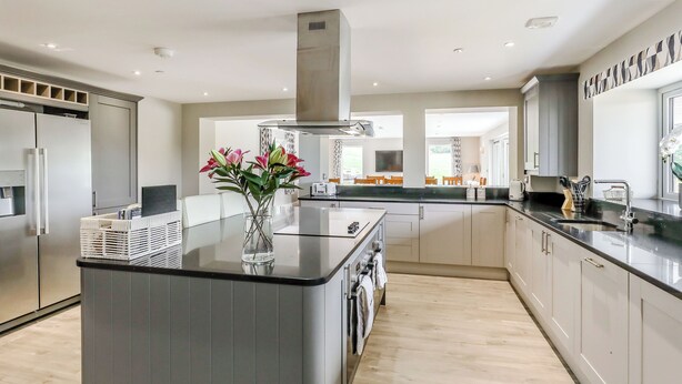 Een moderne keuken met een centraal eiland, roestvrijstalen apparatuur en uitzicht op de eetruimte.
