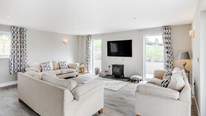 Een ruime woonkamer met een grote bank, een televisie en een open haard.