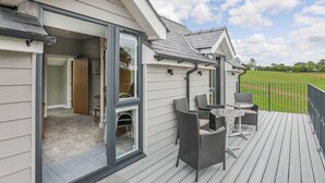 Een overdekt terras buiten met rieten meubilair en uitzicht op een groen veld.