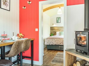 Una habitación acogedora con comedor, una cama con cabecera de madera, chimenea y pared de acento roja.
