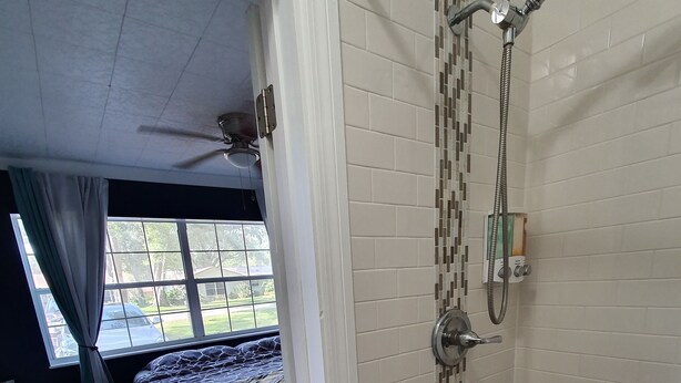 A hotel room with a shower, a bed, a desk, and a window with curtains. - Your Quiet Place with private entrance (Brandon)