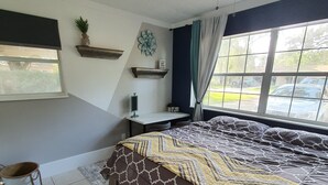 A bedroom with a bed, a ceiling fan, a window with curtains, a small shelf, and a potted plant. - Your Quiet Place with private entrance (Brandon)
