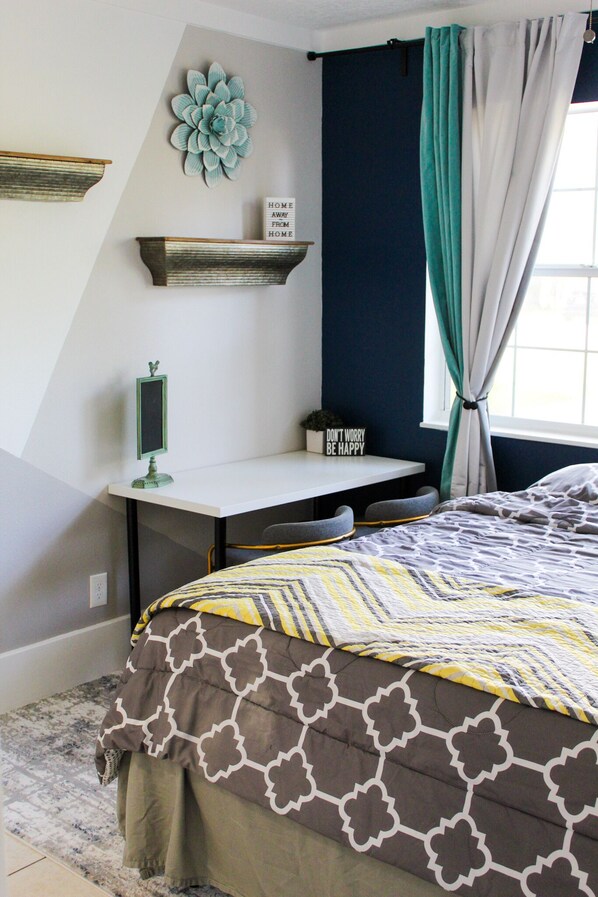 Une chambre à coucher avec un lit, un bureau et une fenêtre avec des rideaux.