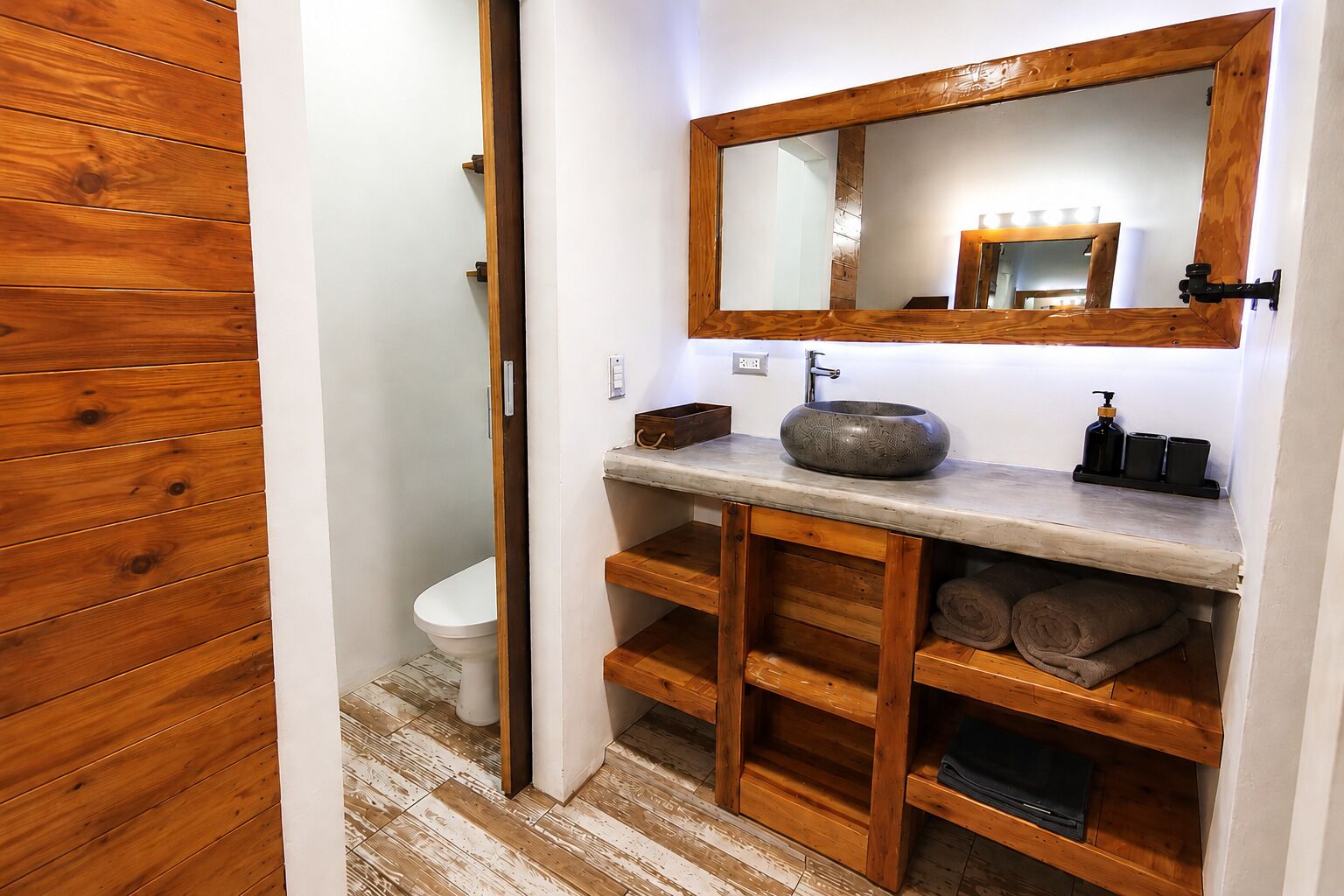 Ein Badezimmer mit einem Holzlagerflächen, einem Vessel-Waschbecken und einem Spiegel.