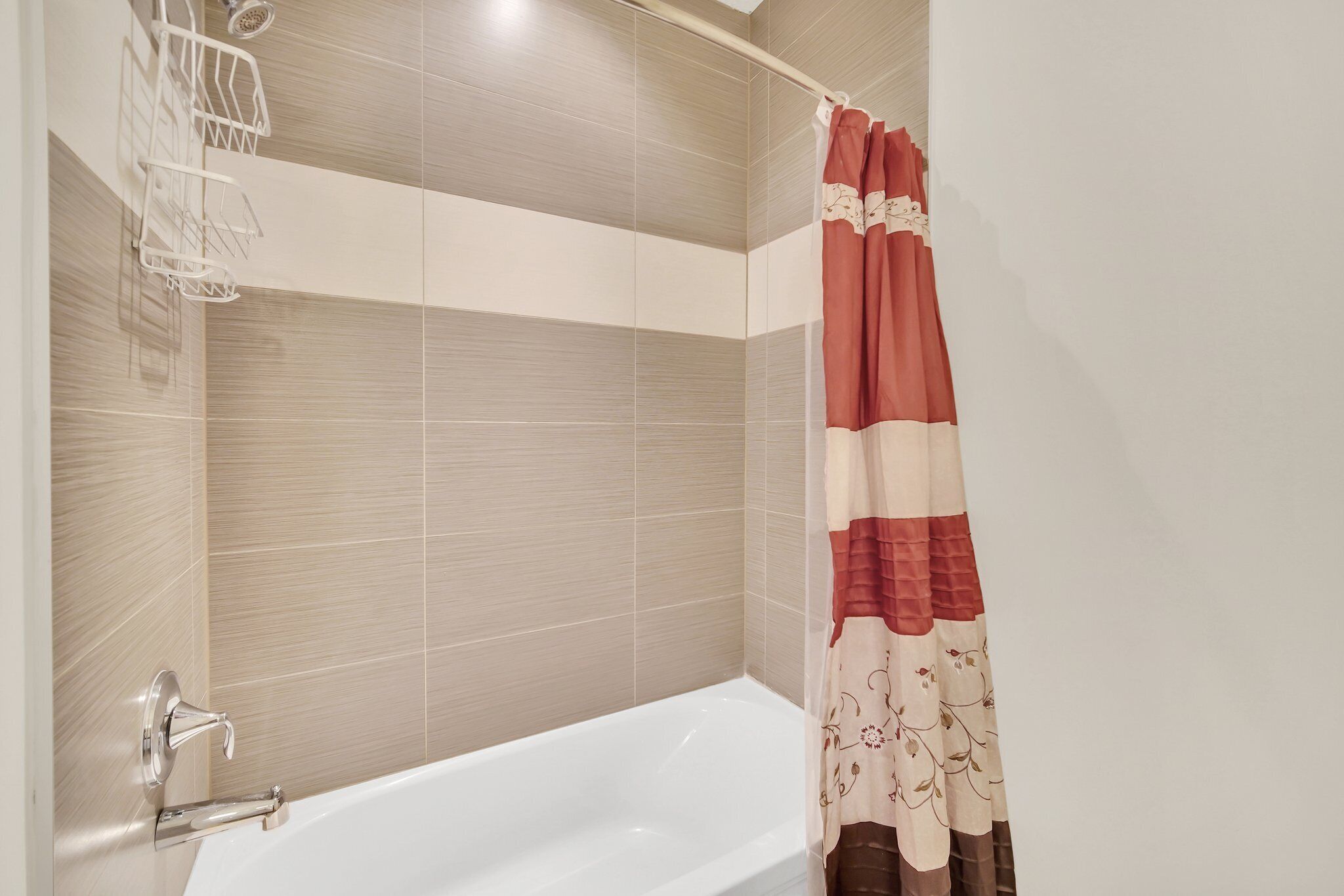 Ein Badezimmer mit einer Badewanne, einer Duschvorhang und einem Metallregal.