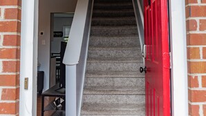 Eine Treppe, die zu einer oberen Etage führt, mit einer roten Tür am unteren Ende.