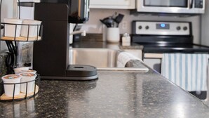 Eine Küche mit Kaffeemaschine, Mikrowelle und Edelstahlgeräten.