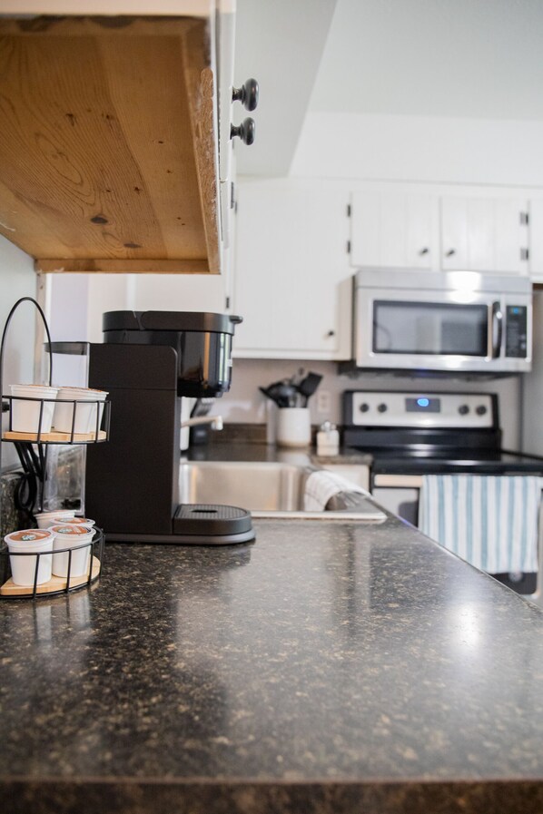 A kitchen with a coffee maker, microwave, and stainless steel appliances.