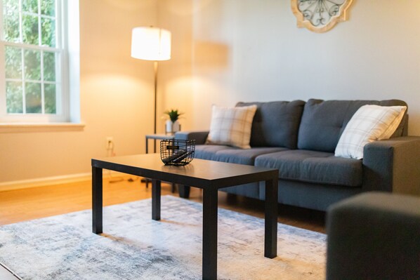 A modern living room with a dark sofa, a small table, and a lamp.