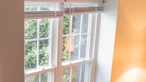 Ein Zimmer mit großem Fenster, weißen Wänden und Holzboden.