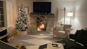 Ein gemütlicher Wohnraum mit Kamin, Weihnachtsbaum und einem Hund.