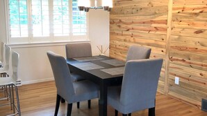 Ein Essbereich mit einer Holzwand, einem Tisch mit vier Stühlen und einer Deckenleuchte.