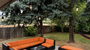 Eine Terrassengruppe mit Ecksofa und Couchtisch, umgeben von Bäumen und einer Hängematte.
