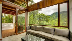 Una habitación moderna con un ventanal grande, un sofá y un jacuzzi.