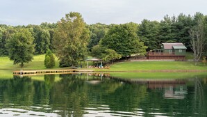 A lakeside view with a house, a covered pavilion, and a dock.