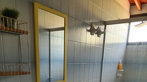 A bathroom with a sink, toilet, and shower. There is a mirror above the sink, and a towel rack with a plant. - Hotel campestre (Copacabana)
